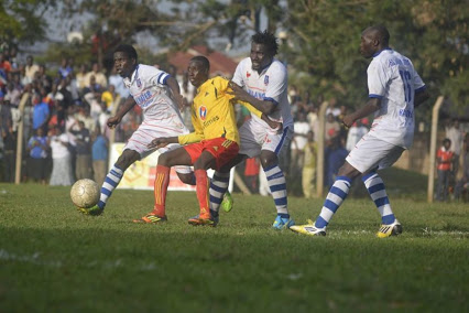 KCC's Nsibambi (Yellow) Shields the ball from SC Villa players