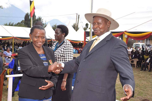 Museveni shakes hands with Lucy Nakyobe the state house financial Comptroller after receiving a medal of exemplary service.